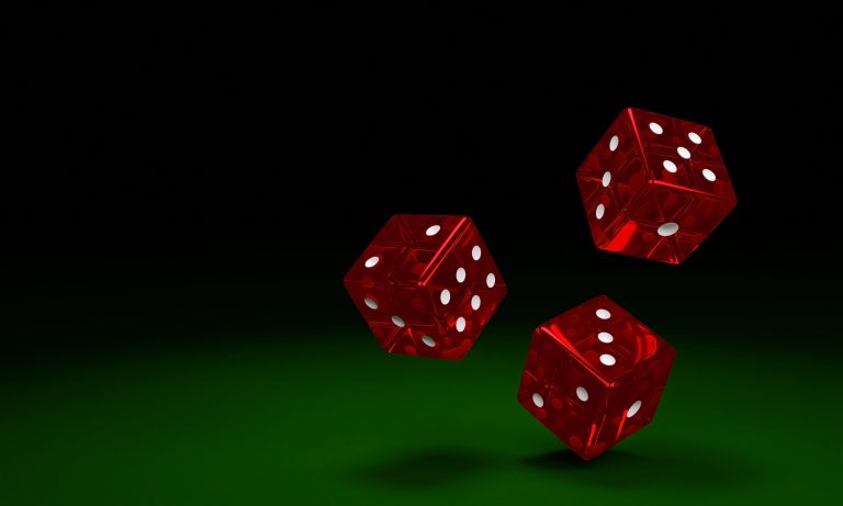 Transparent red dice are falling on the green felt table